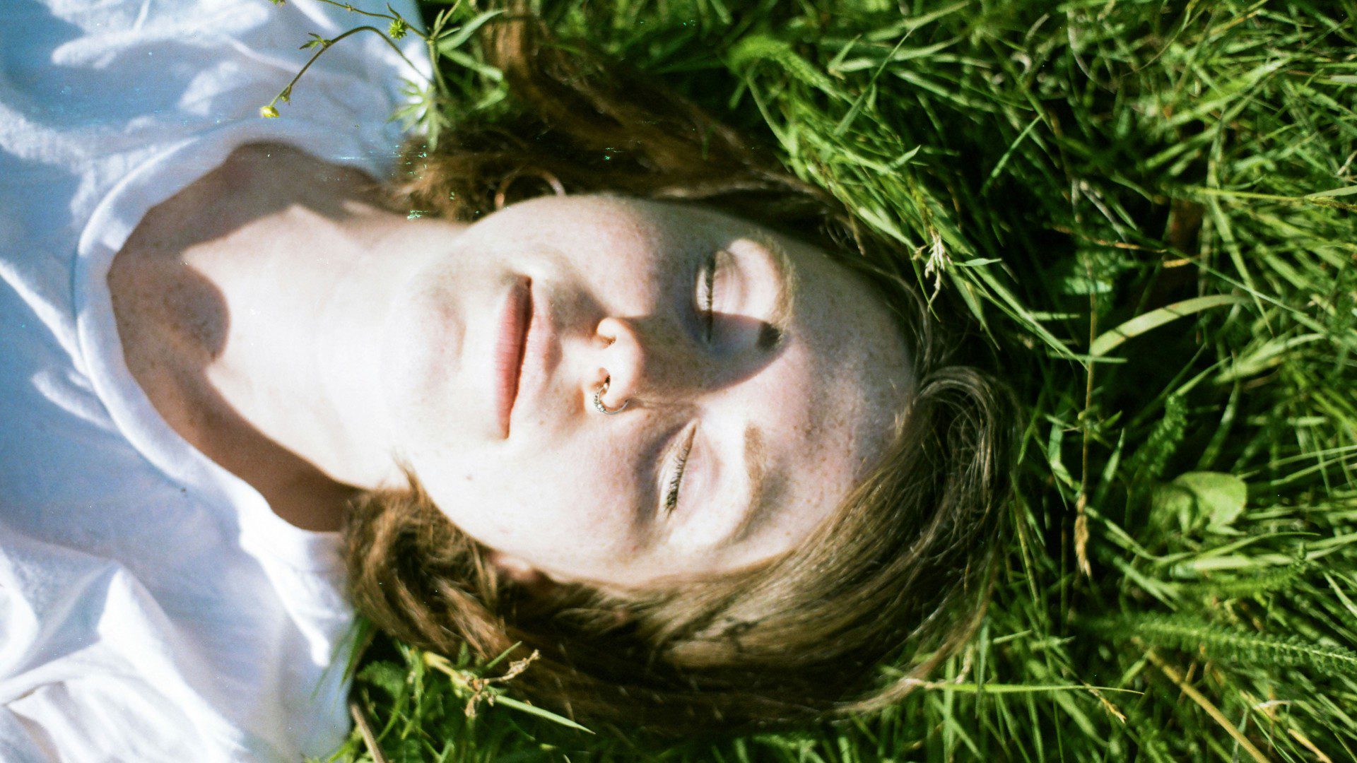 Woman lying on grass relaxing with eyes closed