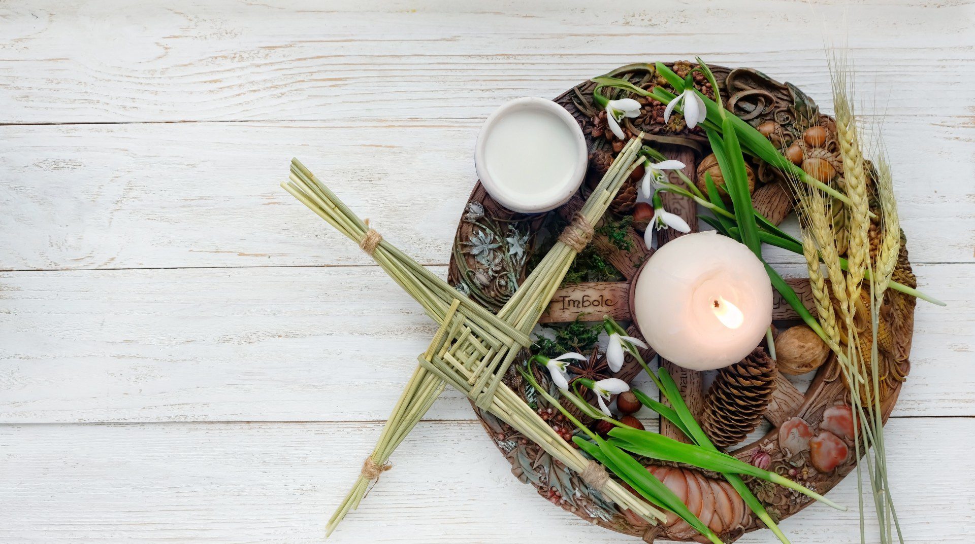 Photo of a Brigid's cross, platter, candle and Imbolc plaque