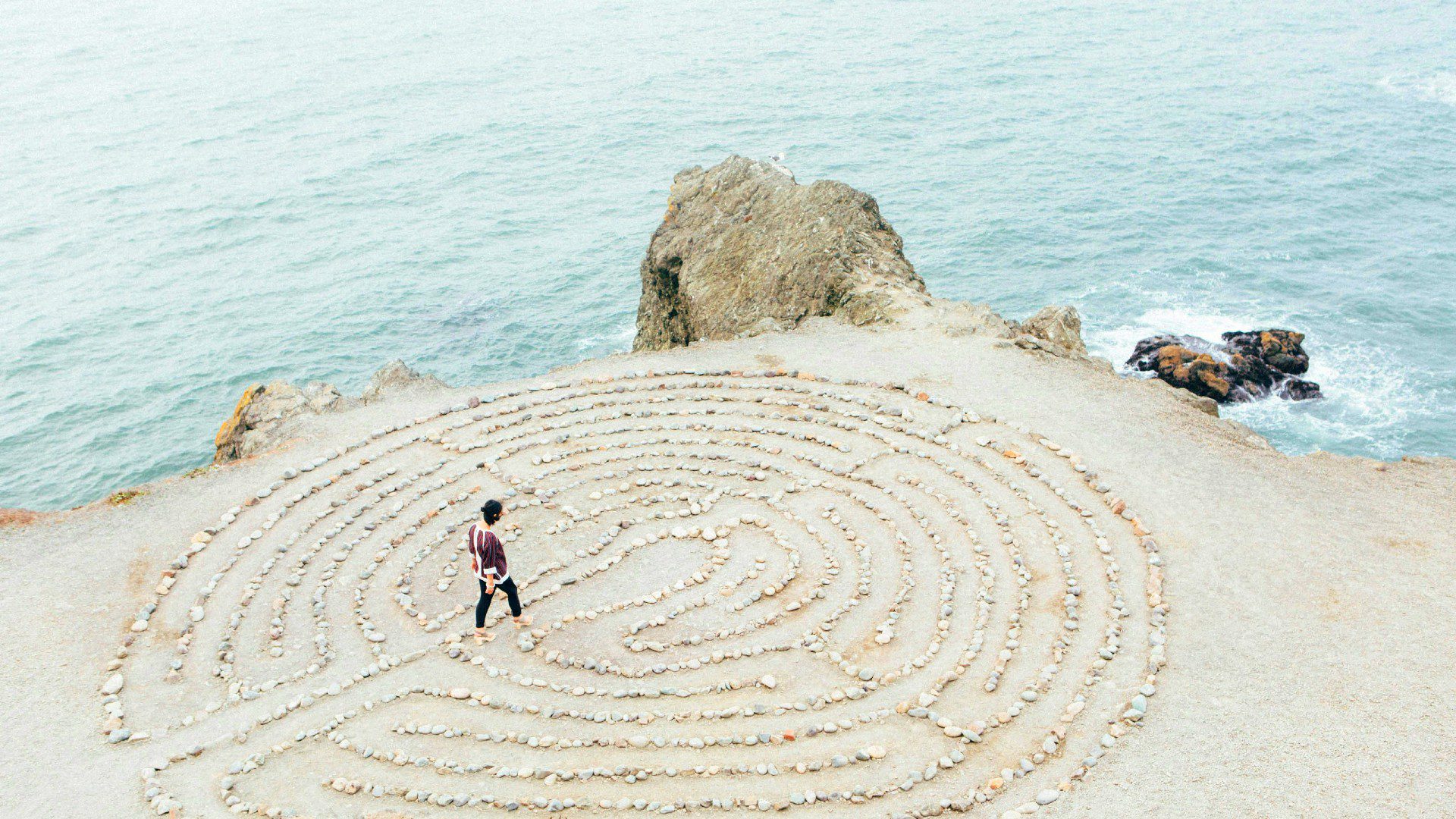 Person walking a labyrinth by the sea