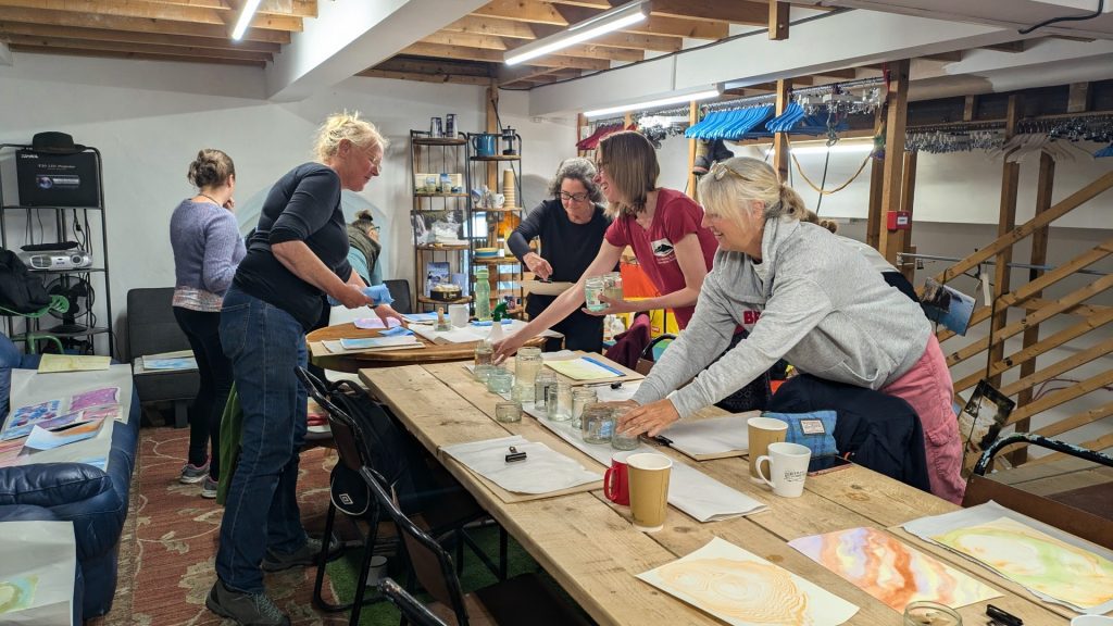 Creativity and nature workshop participants having a laugh together while setting up natural inks on the table